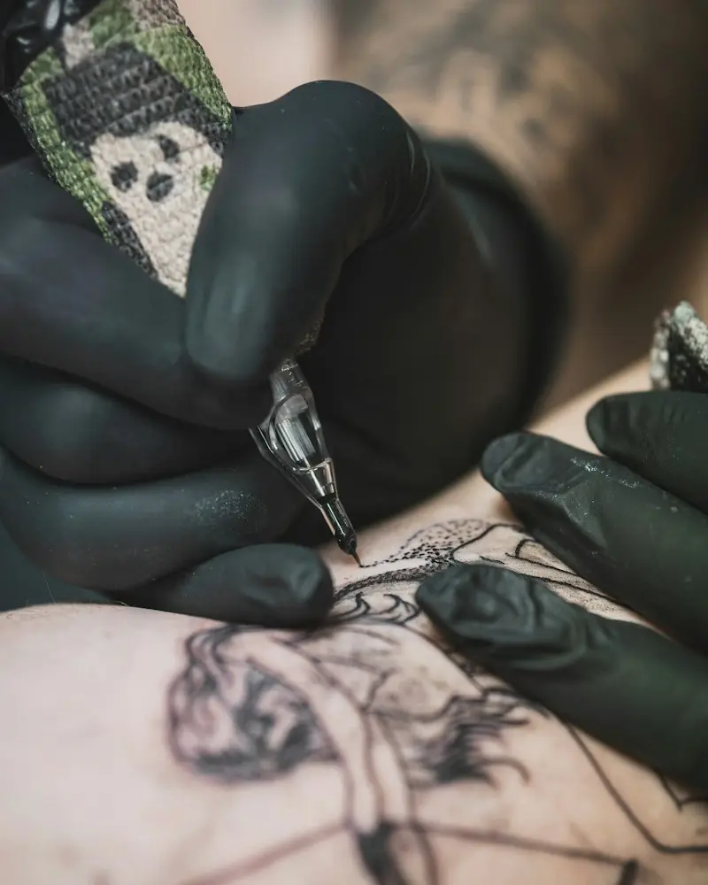 Tatuador com luvas pretas tatuando